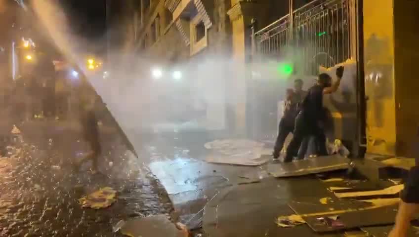 Protesters against Georgia’s foreign agent law have tried to barricade an entrance to the Georgian Parliament, as police inside the courtyard deploy water cannons to push the crowds away from the gate