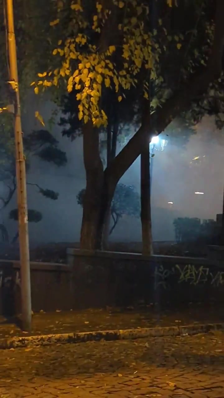 Riot police are facing groups of protesters from two sides. Protesters fire fireworks while police shoot tear gas grenades. Nini Gabritchidze/Civil.ge