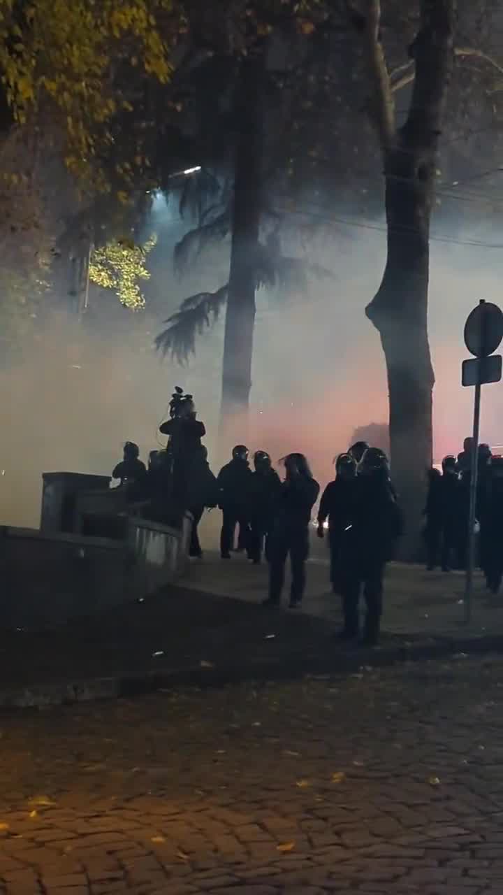 Riot police are facing groups of protesters from two sides. Protesters fire fireworks while police shoot tear gas grenades. Nini Gabritchidze/Civil.ge