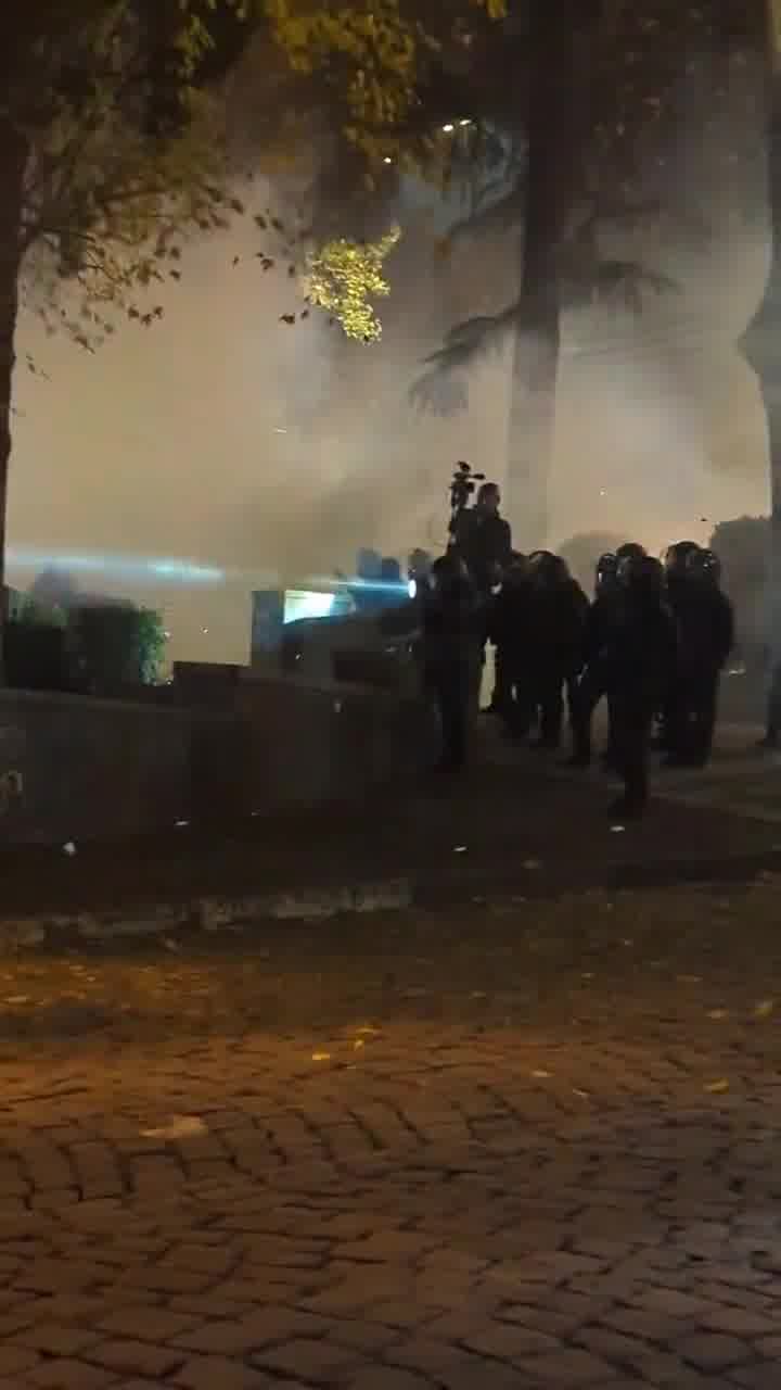 Riot police are facing groups of protesters from two sides. Protesters fire fireworks while police shoot tear gas grenades. Nini Gabritchidze/Civil.ge