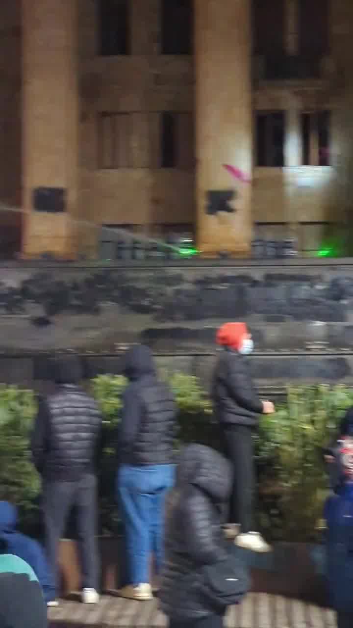 Riot police again pouring streams of water at protesters from inside the parliament. Water cannons also mobilized, and protesters occasionally fire fireworks at the parliament