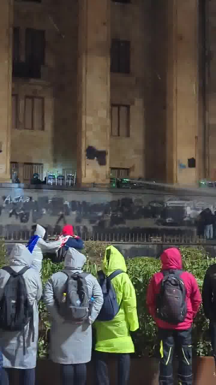 Riot police again pouring streams of water at protesters from inside the parliament. Water cannons also mobilized, and protesters occasionally fire fireworks at the parliament